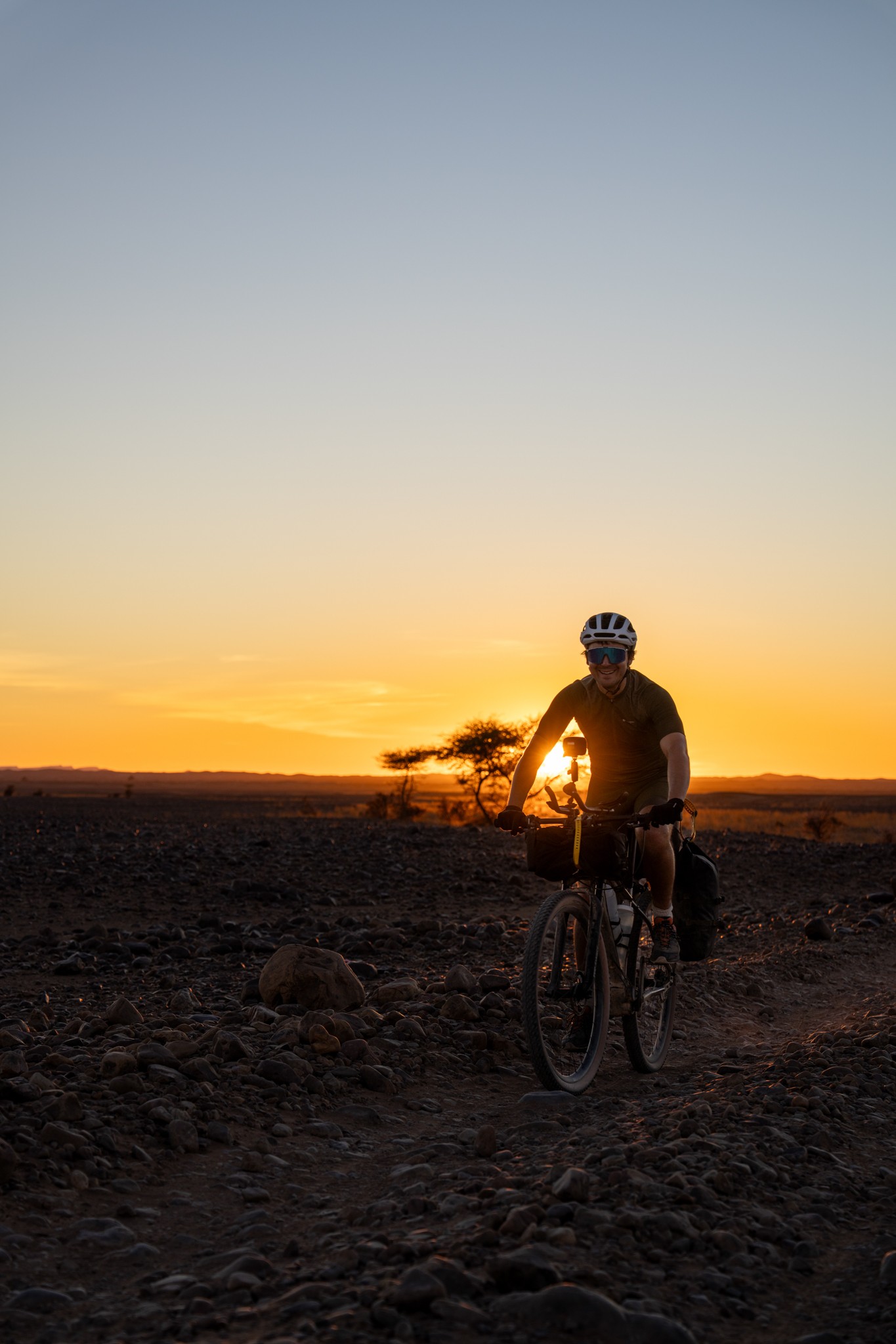 Cyclist riding into sunset in the Sahara